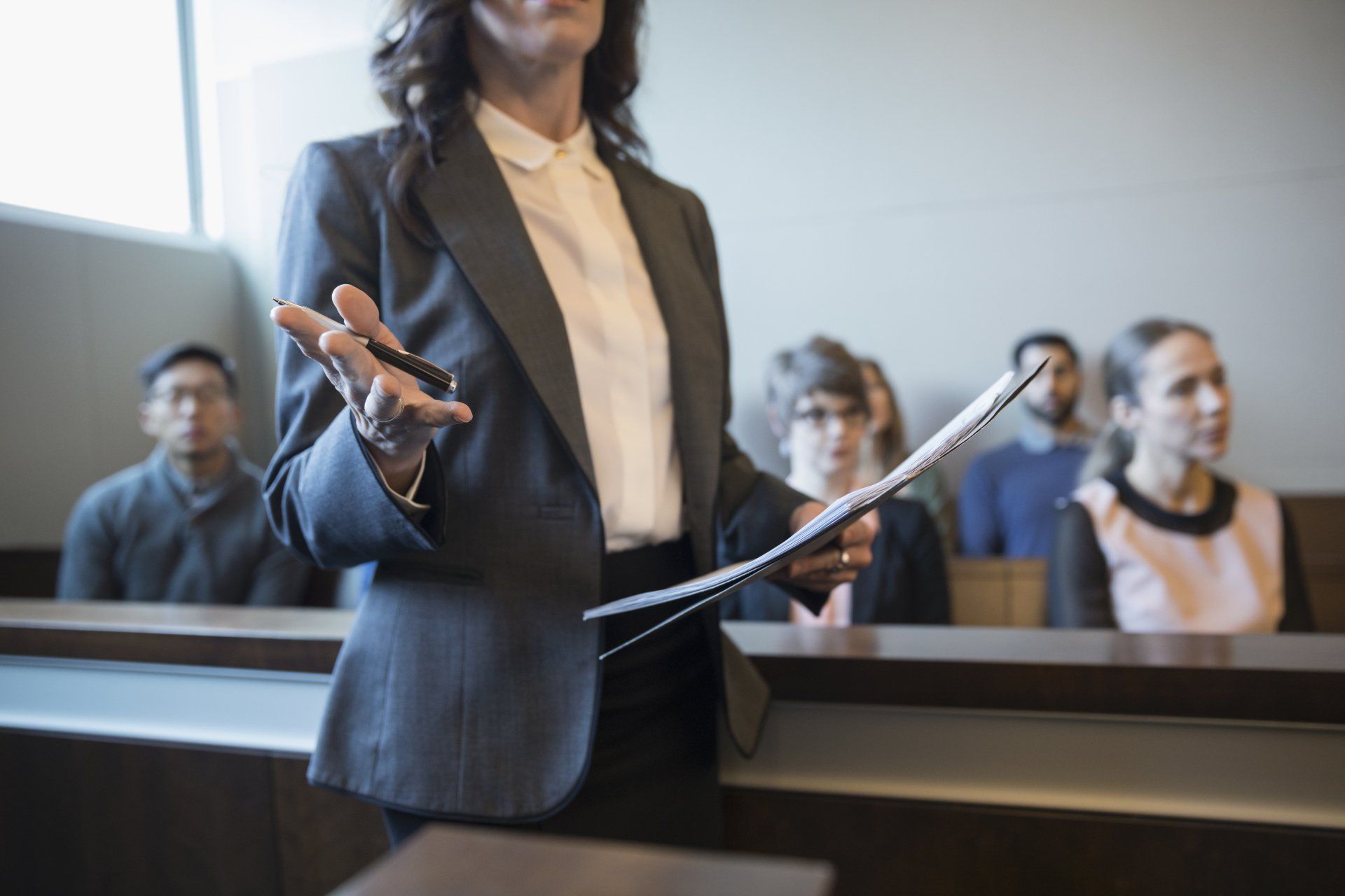 Femme tendant une main avec stylo et dans l'autre des papiers dans une cour de justice