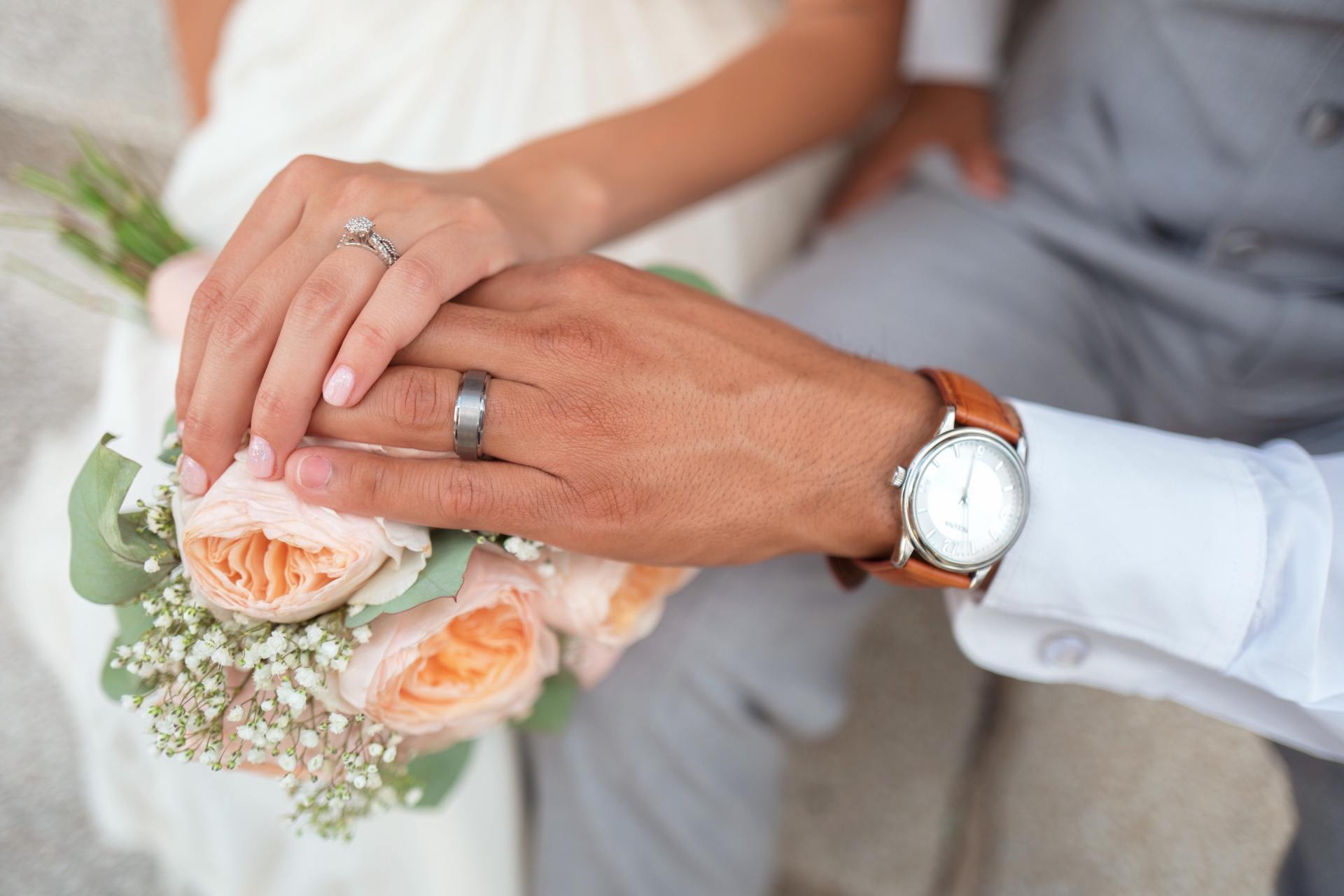 Mariés posant leur main sur un bouquet