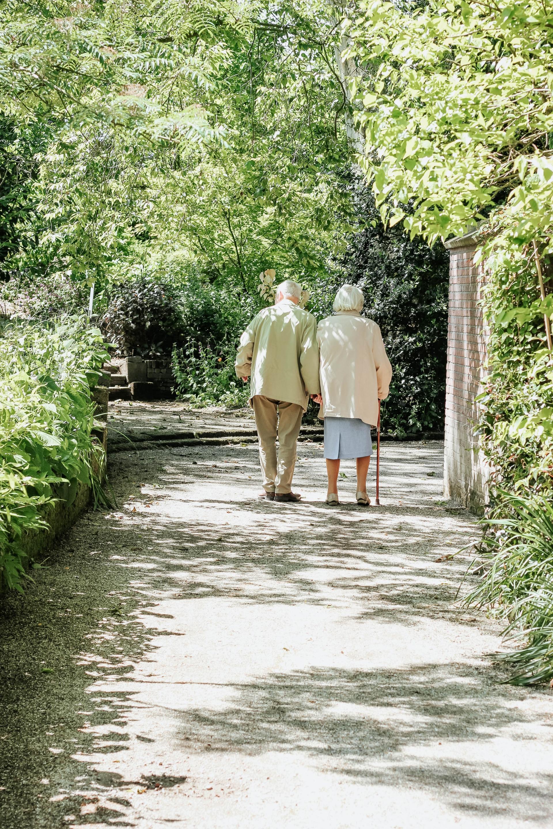 Pflegefachkraft unterstützt alte Person beim Gehen mit der Gehhilfe